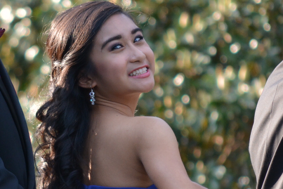 Girl wearing a blue dress looking over her shoulder.